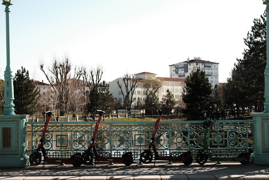 Ornate railing with scooters in a park setting, urban area, bright day.